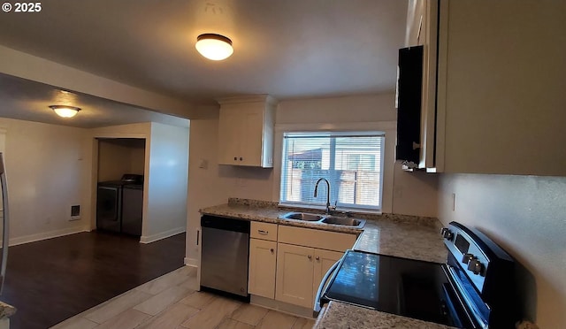 kitchen featuring a sink, appliances with stainless steel finishes, washer and clothes dryer, and white cabinets
