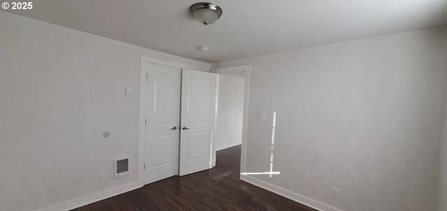 unfurnished bedroom featuring baseboards and dark wood-type flooring