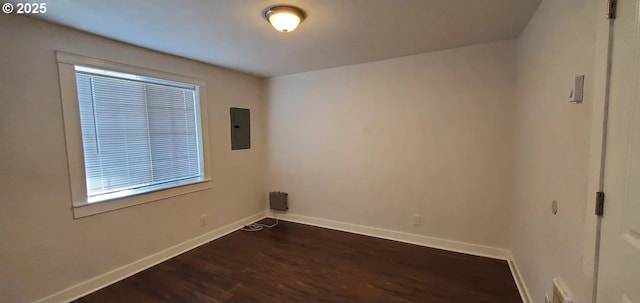 spare room with dark wood-type flooring, baseboards, and electric panel