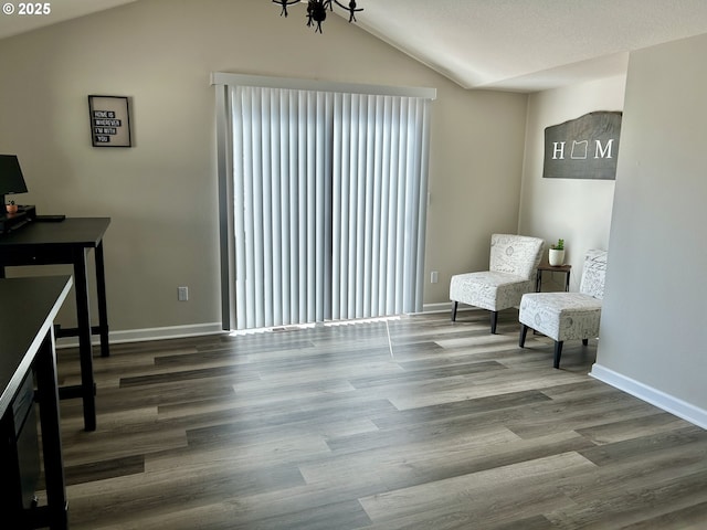 living area with vaulted ceiling, baseboards, and wood finished floors