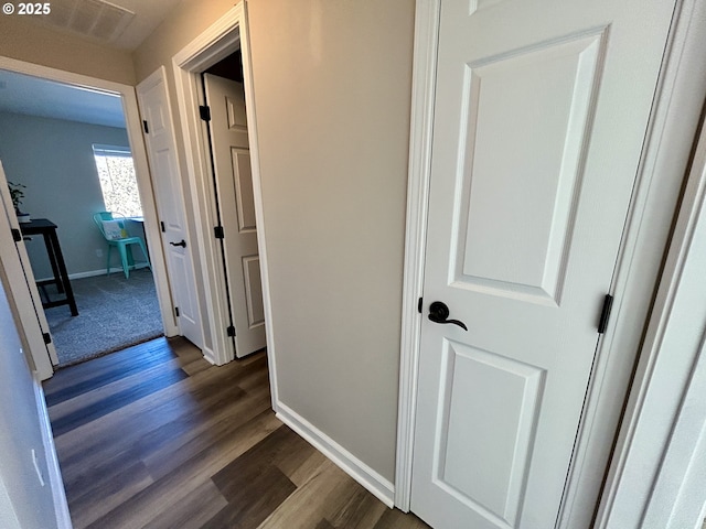 corridor featuring dark wood finished floors and baseboards