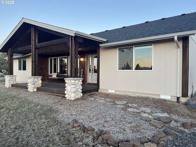 rear view of house with a shingled roof and covered porch