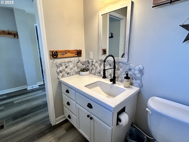 bathroom with toilet, baseboards, wood finished floors, and vanity