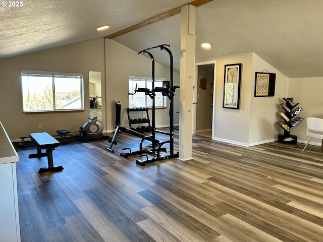 workout area featuring vaulted ceiling, a healthy amount of sunlight, wood finished floors, and baseboards