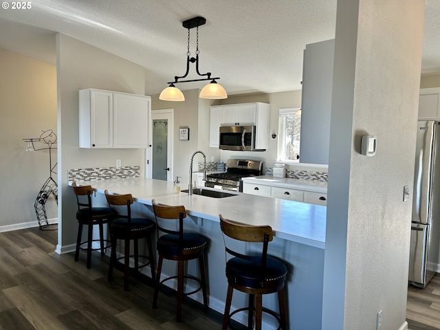 kitchen featuring stainless steel appliances, dark wood-style flooring, white cabinetry, and a sink