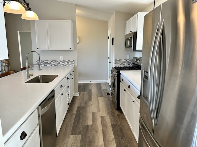 kitchen with dark wood-style flooring, a sink, white cabinetry, light countertops, and appliances with stainless steel finishes