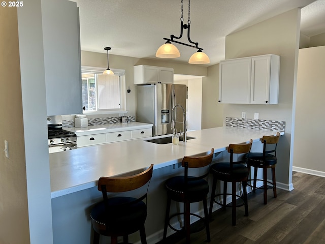 kitchen featuring dark wood finished floors, white cabinets, a peninsula, stainless steel appliances, and a sink