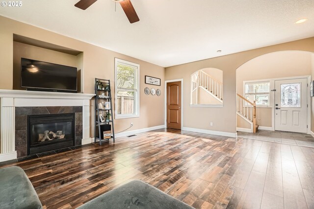 living area featuring ceiling fan, stairway, wood finished floors, and a healthy amount of sunlight