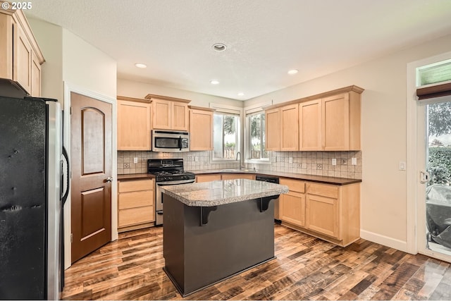 kitchen featuring light brown cabinetry, appliances with stainless steel finishes, and dark wood-type flooring