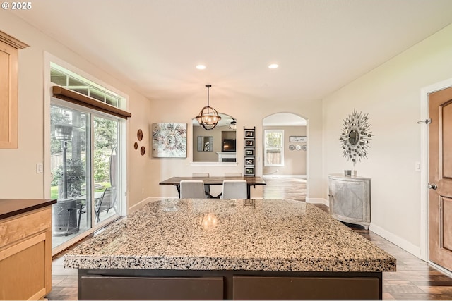 kitchen featuring recessed lighting, a kitchen island, pendant lighting, arched walkways, and wood finished floors
