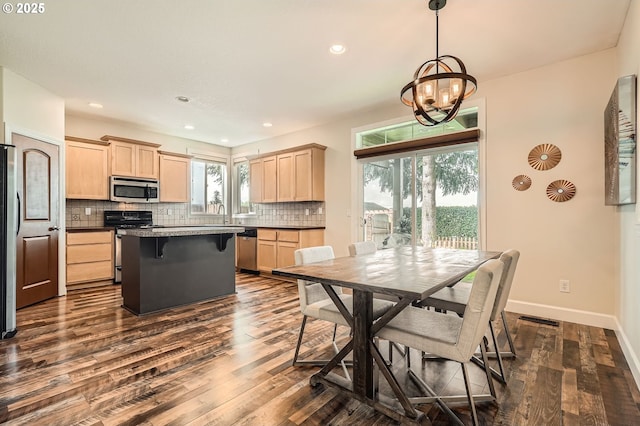 kitchen featuring dark wood-style floors, an inviting chandelier, stainless steel appliances, decorative backsplash, and light brown cabinetry
