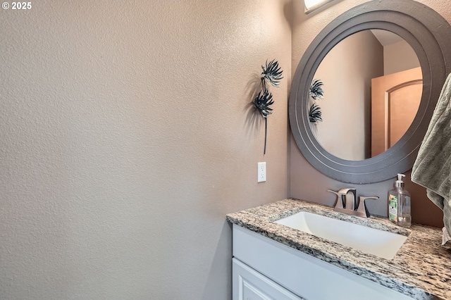 bathroom with a textured wall and vanity