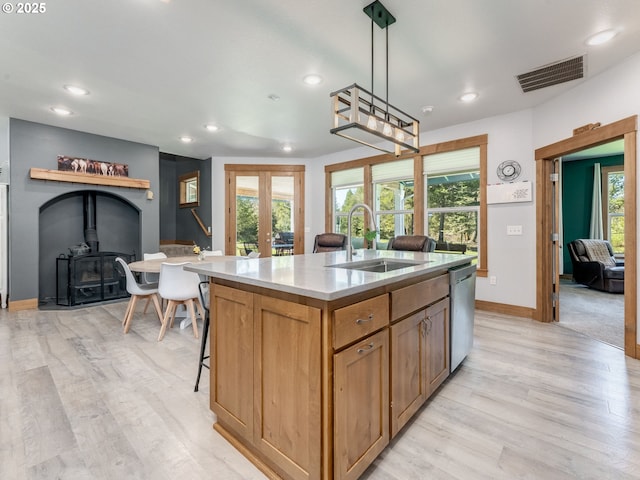 kitchen featuring stainless steel dishwasher, a sink, a wood stove, visible vents, and recessed lighting