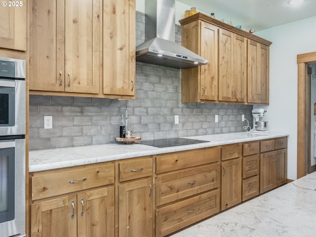 kitchen with light stone counters, double oven, black electric cooktop, backsplash, and wall chimney exhaust hood