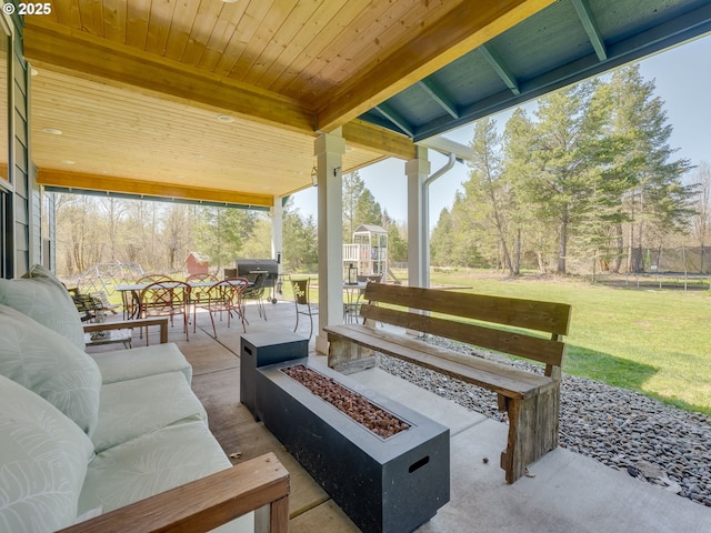 view of patio / terrace featuring area for grilling, an outdoor living space with a fire pit, outdoor dining space, and a trampoline