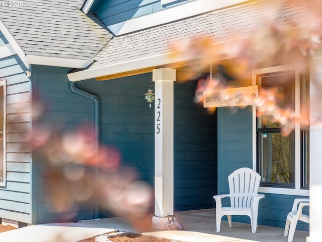 entrance to property with roof with shingles and a porch