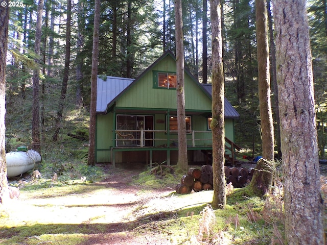 chalet / cabin with covered porch, metal roof, and a view of trees