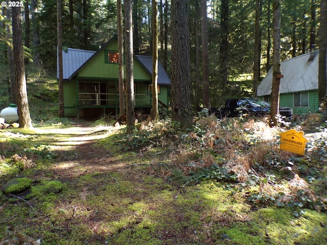 view of yard with covered porch and a wooded view