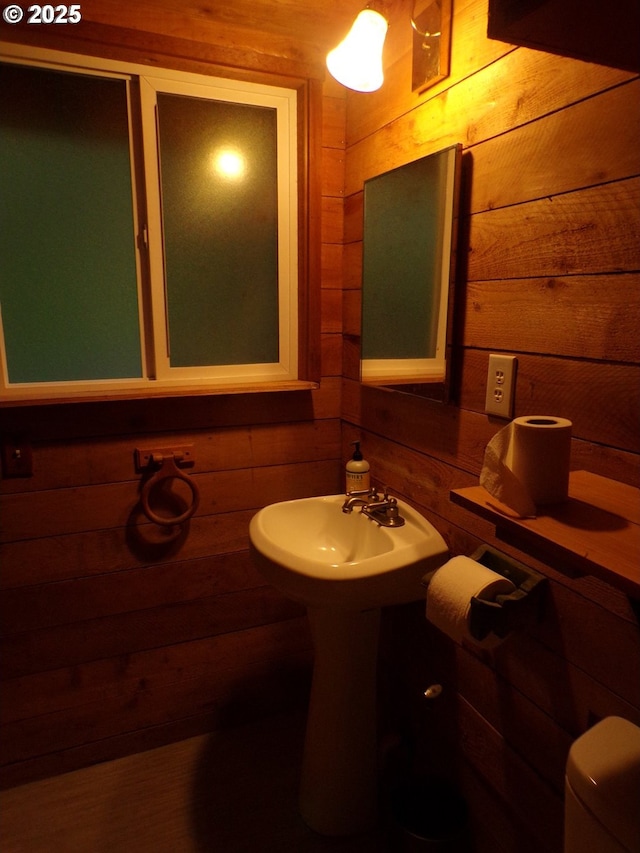 half bathroom with toilet and wood walls