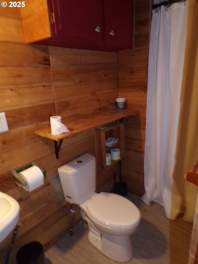 bathroom with a shower with shower curtain, toilet, and wooden walls