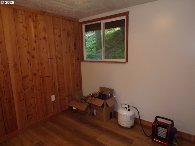 unfurnished room with wood walls, a textured ceiling, and wood finished floors