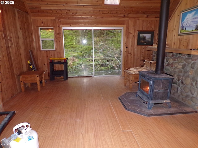 living area featuring a wood stove, wooden walls, and wood finished floors