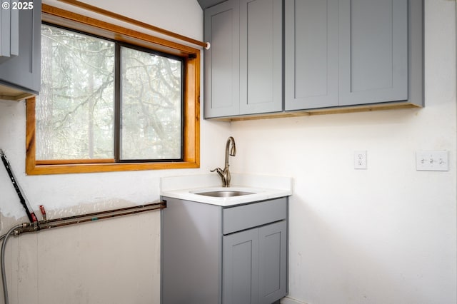 clothes washing area featuring cabinets and sink