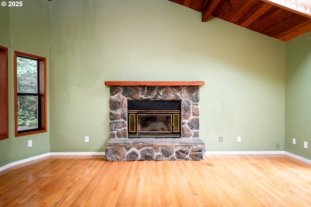 unfurnished living room featuring wood-type flooring, a stone fireplace, wooden ceiling, and beam ceiling