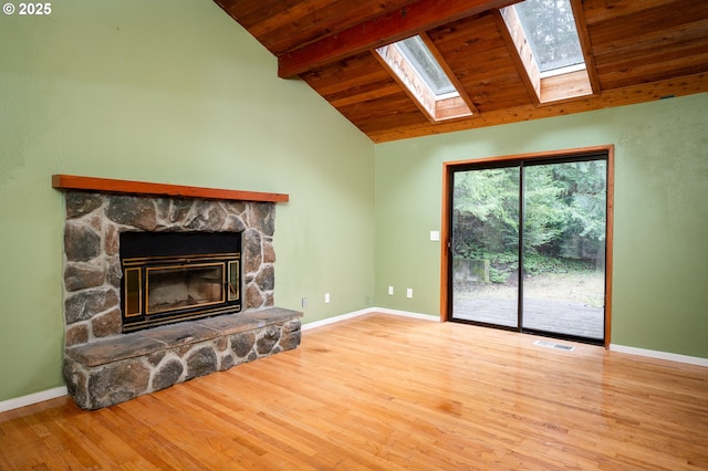 unfurnished living room featuring a stone fireplace, a skylight, light hardwood / wood-style flooring, wooden ceiling, and beamed ceiling