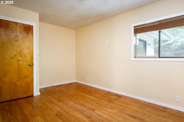 unfurnished room with wood-type flooring and a textured ceiling