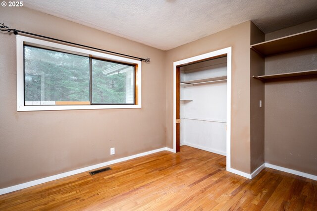 unfurnished bedroom with hardwood / wood-style flooring and a textured ceiling