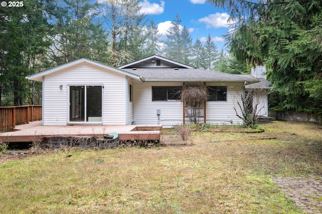 rear view of property featuring a wooden deck and a lawn