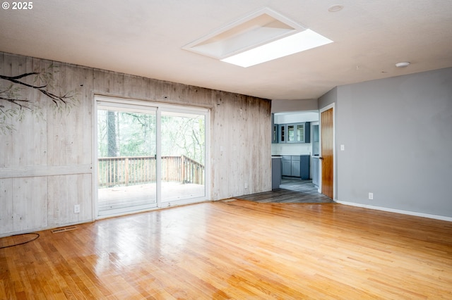 unfurnished living room with a skylight and hardwood / wood-style floors