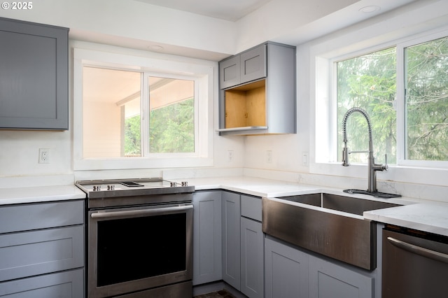 kitchen with gray cabinetry, sink, stainless steel appliances, and a healthy amount of sunlight