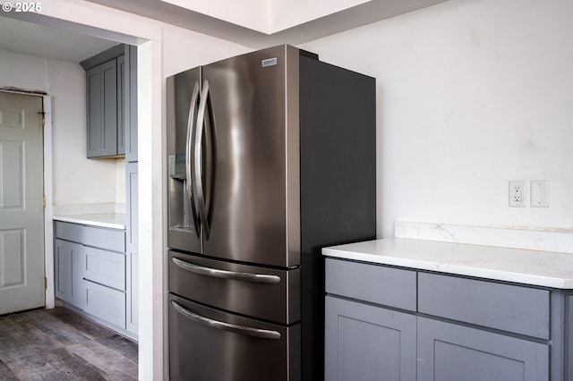 kitchen featuring gray cabinets, light stone countertops, dark wood-type flooring, and stainless steel fridge