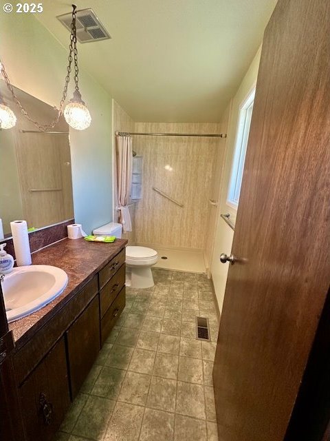 bathroom featuring a walk in shower, toilet, vanity, and visible vents