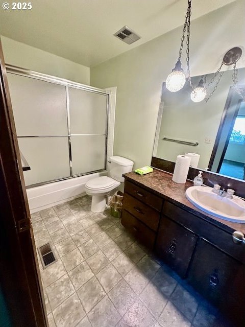 bathroom featuring visible vents, vanity, toilet, and combined bath / shower with glass door