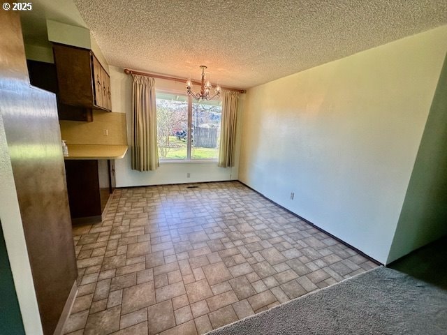 unfurnished dining area featuring brick floor, a notable chandelier, and a textured ceiling