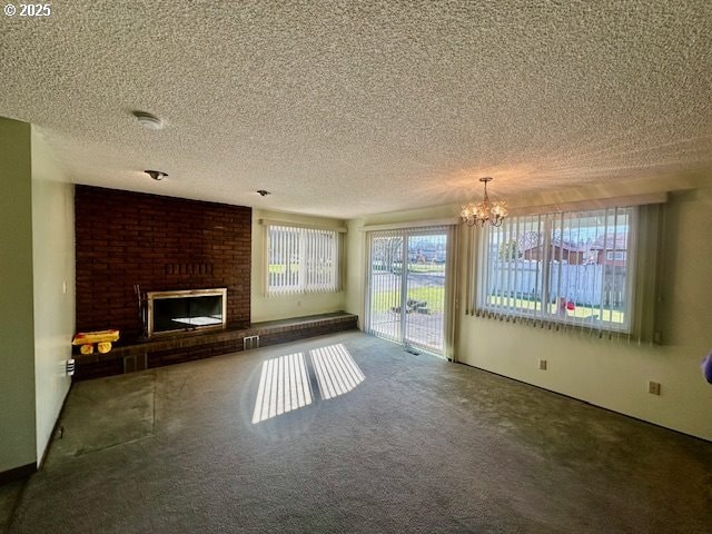 unfurnished living room with a brick fireplace, carpet, a textured ceiling, and an inviting chandelier