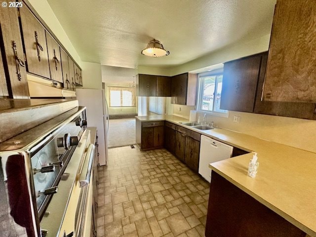 kitchen featuring dishwasher, stove, a peninsula, light countertops, and a sink