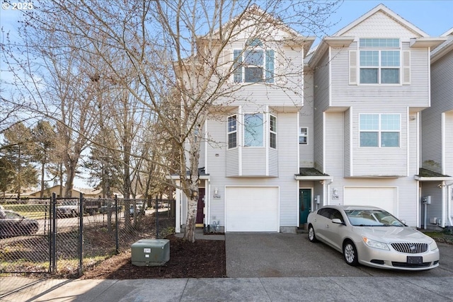 townhome / multi-family property with an attached garage, fence, and aphalt driveway