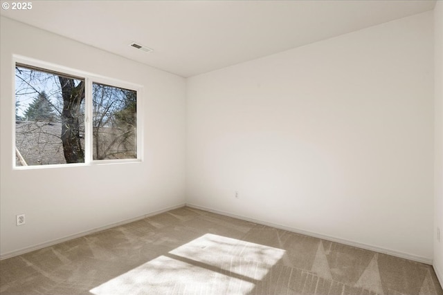 spare room featuring light carpet, visible vents, and baseboards