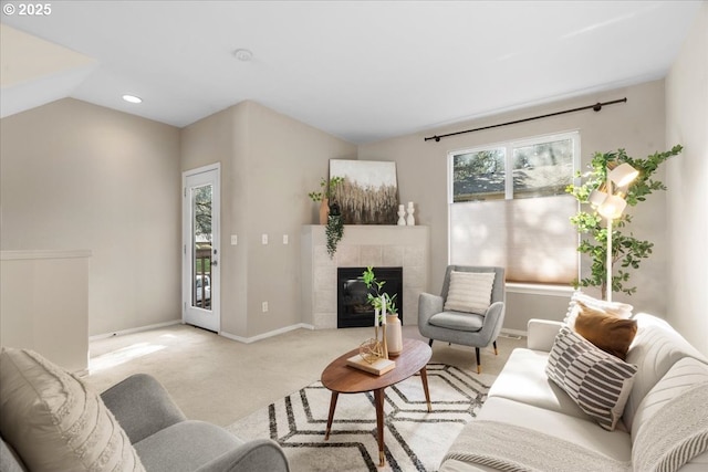 living area featuring vaulted ceiling, light carpet, a fireplace, and baseboards