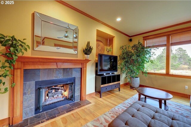 living room with a tile fireplace, ornamental molding, and hardwood / wood-style flooring