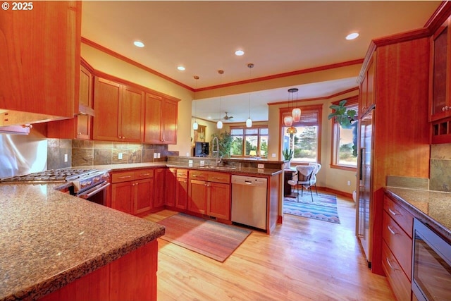 kitchen with light hardwood / wood-style floors, stainless steel appliances, kitchen peninsula, sink, and decorative light fixtures