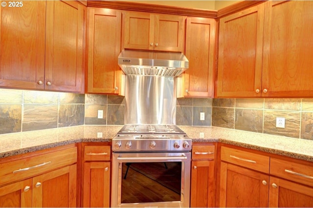 kitchen with backsplash, exhaust hood, stainless steel range with gas stovetop, and light stone counters