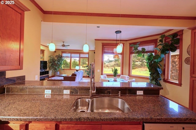 kitchen with sink, decorative light fixtures, dishwasher, dark stone countertops, and crown molding