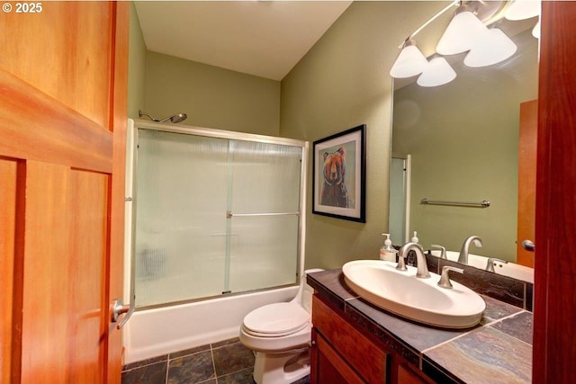 full bathroom with enclosed tub / shower combo, vanity, and toilet