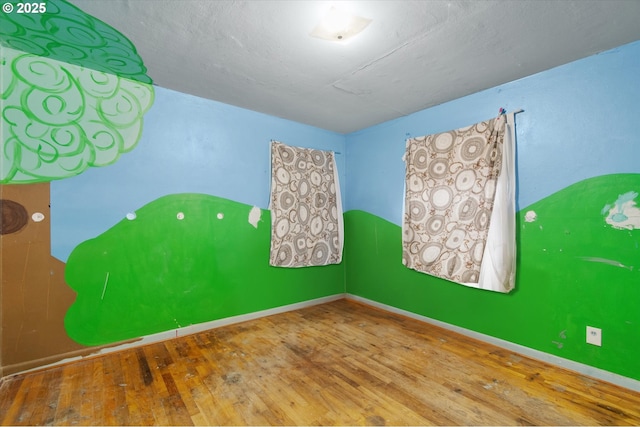 spare room featuring hardwood / wood-style flooring and baseboards