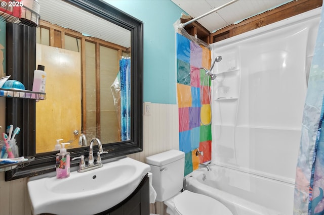 bathroom featuring vanity, wainscoting, shower / bath combo with shower curtain, and toilet